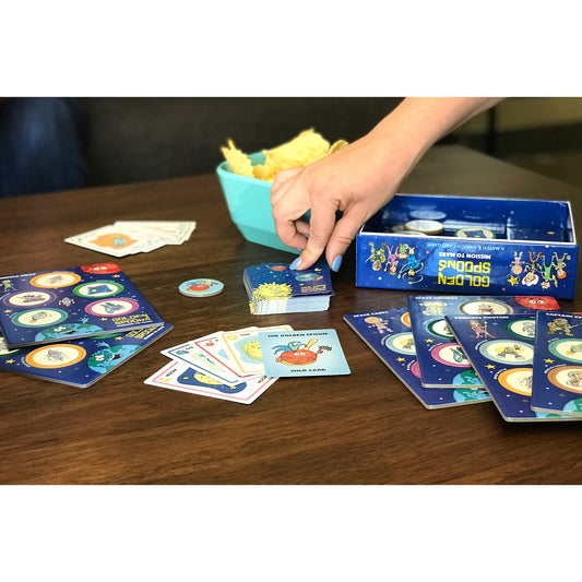 Golden Spoons game is laid out on a table to show cards, tokens, and other items used to play game