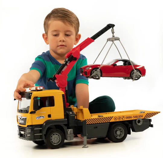 Child plays with realistic model yellow tow truck with red crane arm loading red convertible car onto back