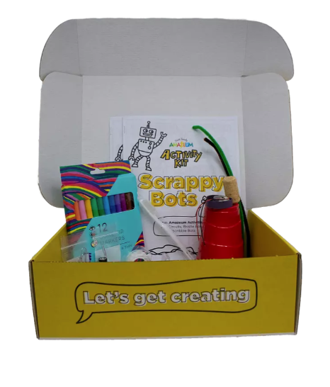 An open box says Let's Get Creating on front edge. Inside of the box, an instruction manual for Scrappy Bots can be seen alongside the materials used to make them. 