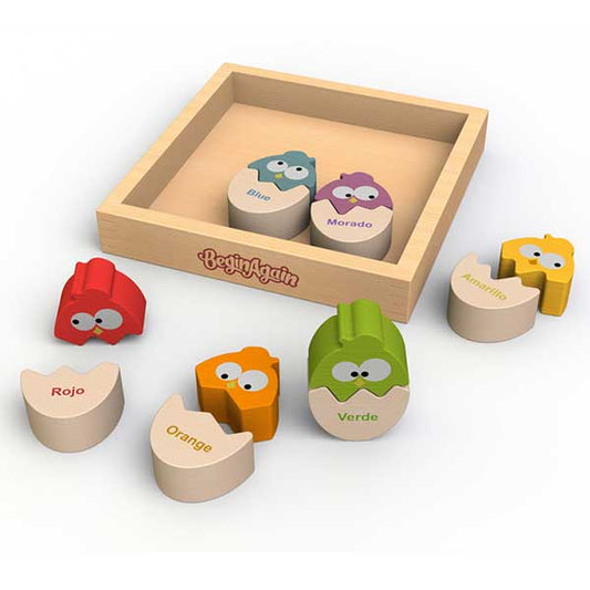 A wooden tray holds brightly colored hatching chick puzzles that have the colors labeled in Spanish and English