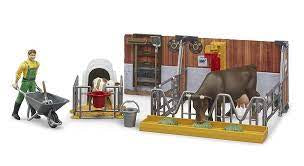 A model farm scene with a cow eating hay and a calf in a veal crate eating from a bucket.